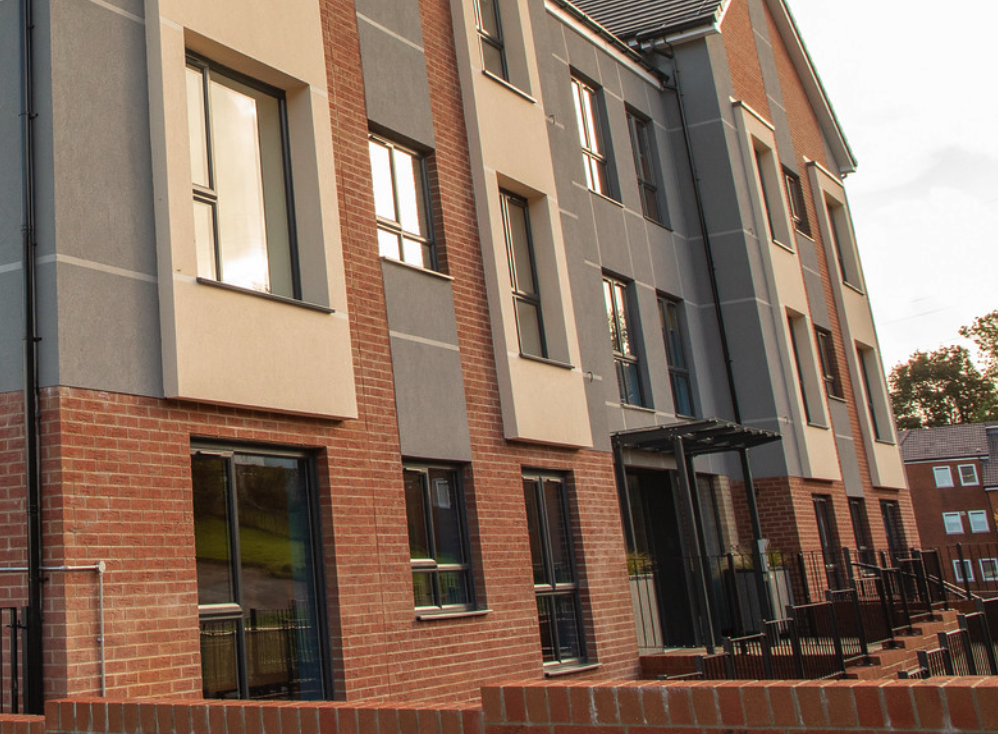 Exterior of a modern red brick and grey rendered apartment building managed by Bron Afon